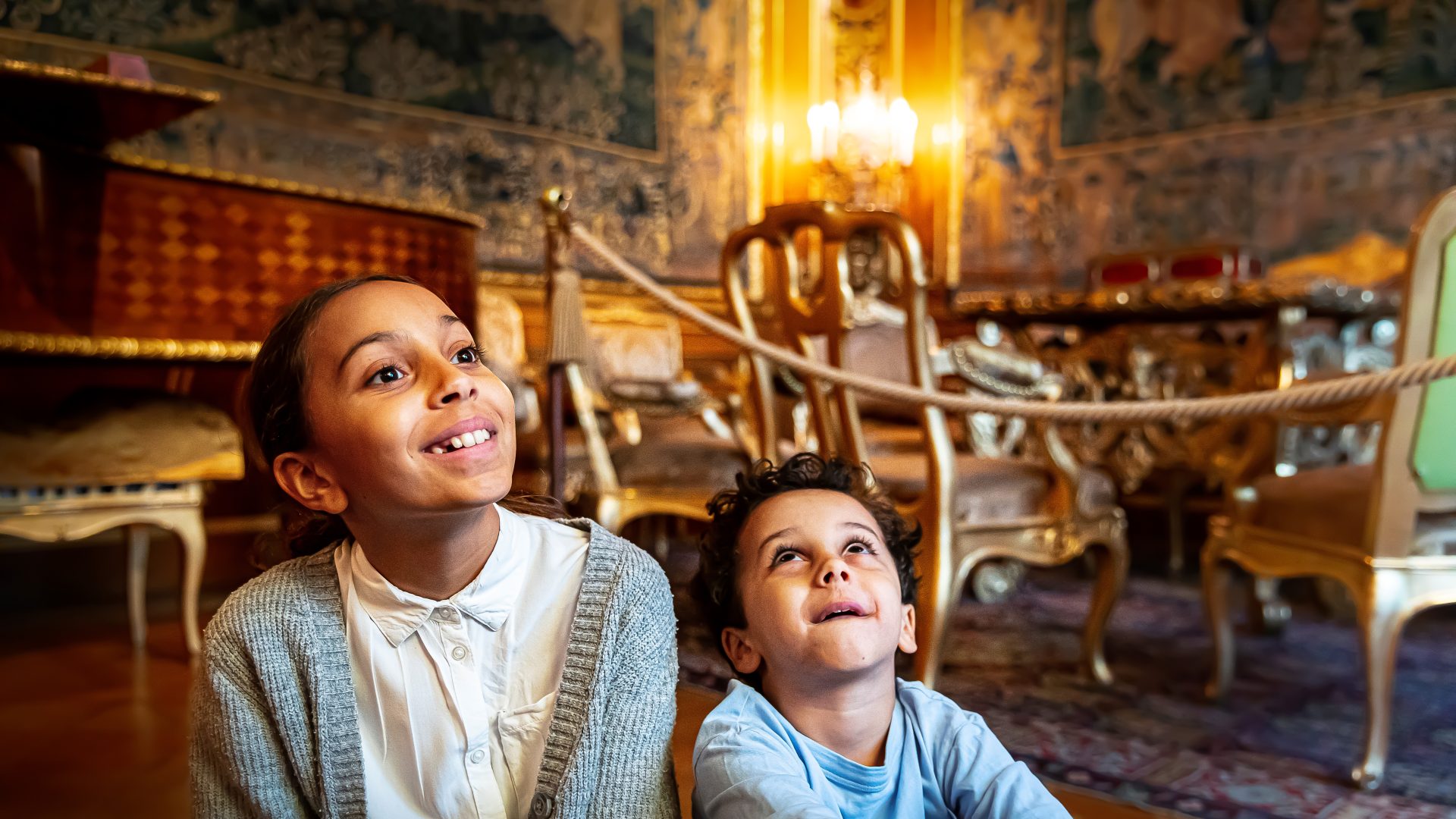 Two children sitting and smiling in the museum's great drawing room