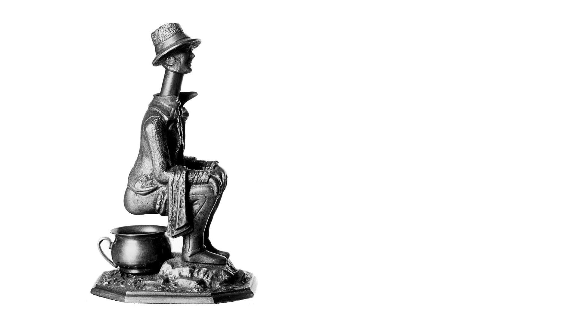En metallfigurin föreställande en man med hög hatt som sitter på en potta. Den används för att snoppa cigarrer.