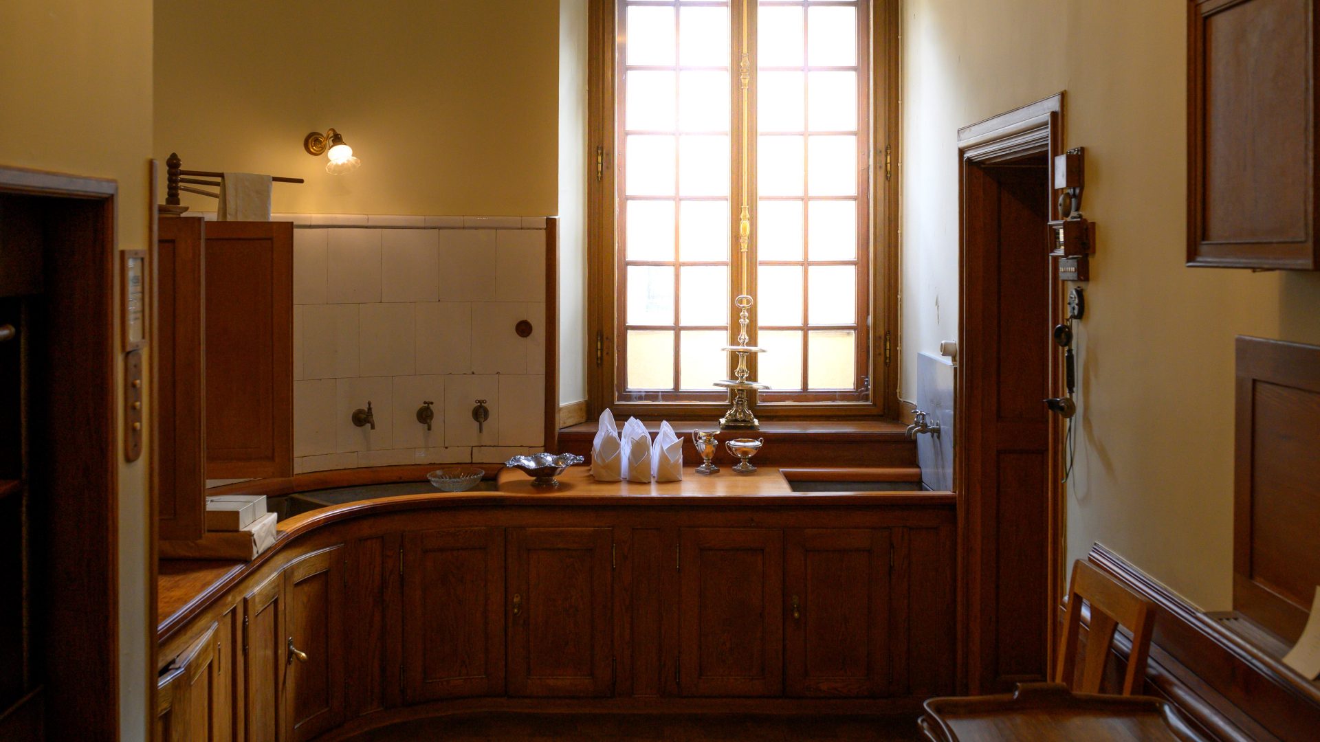 A room with yellow walls and a window. Along the sides a sink and water taps