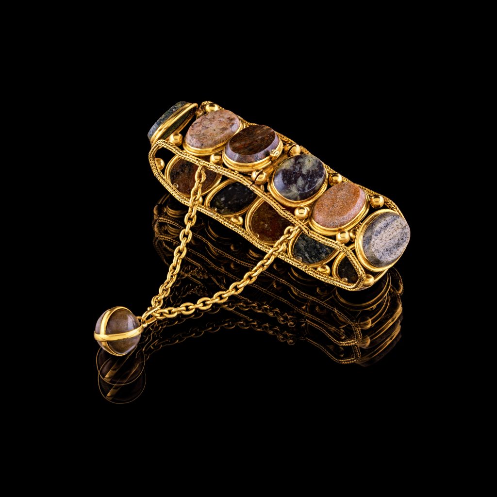 Ett armband av guld med ovala stenar.