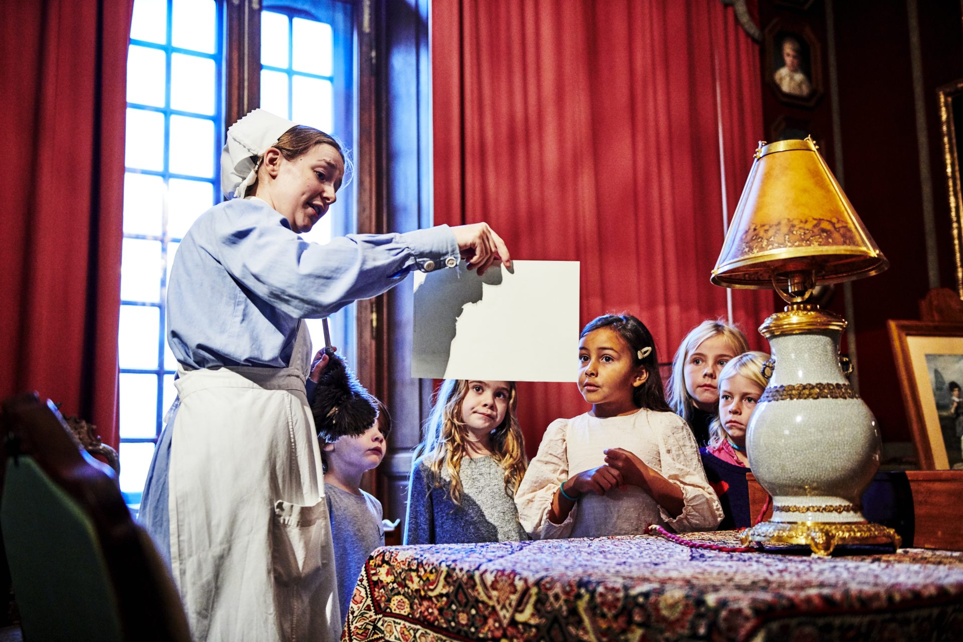 En skolklass som blir guidade i Hallwylska palatset av en guide i historiska kläder.