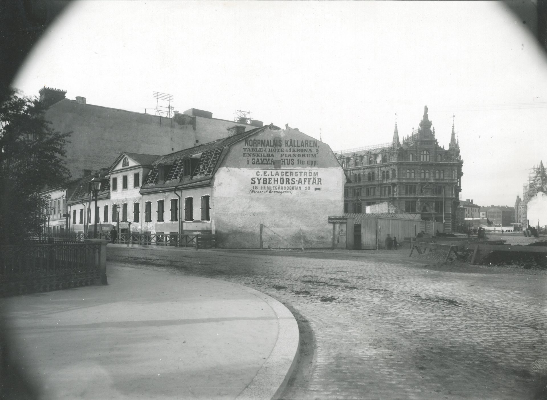 A black and white photo of an elongated building with advertising text on one end. 