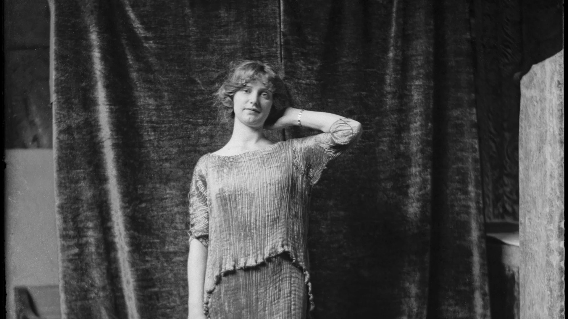 Äldre fotografi av en kvinna som poserar i en klänning gjord av Mariano Fortuny
