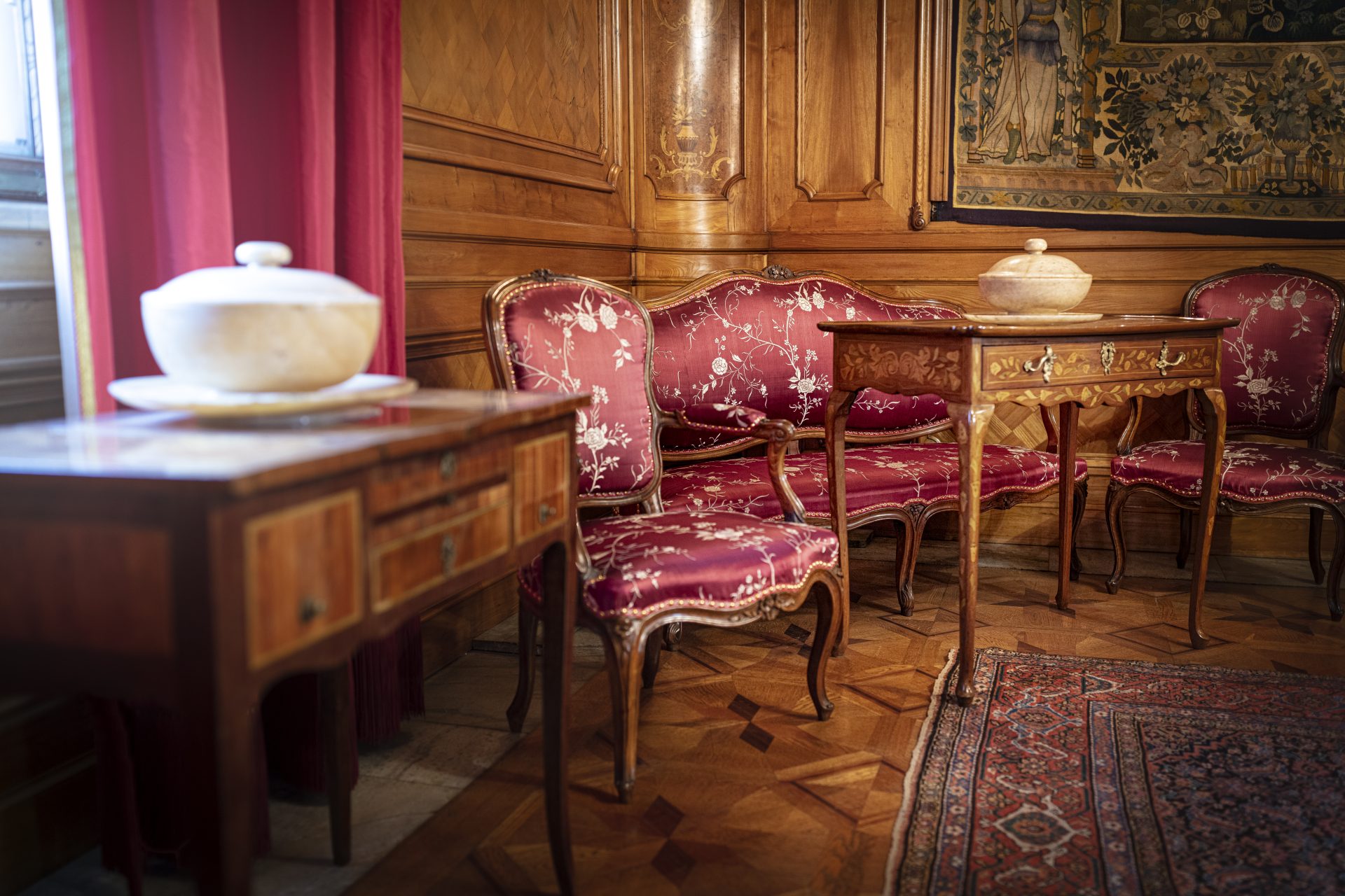 A room with wooden panels and rich, red upholstery.