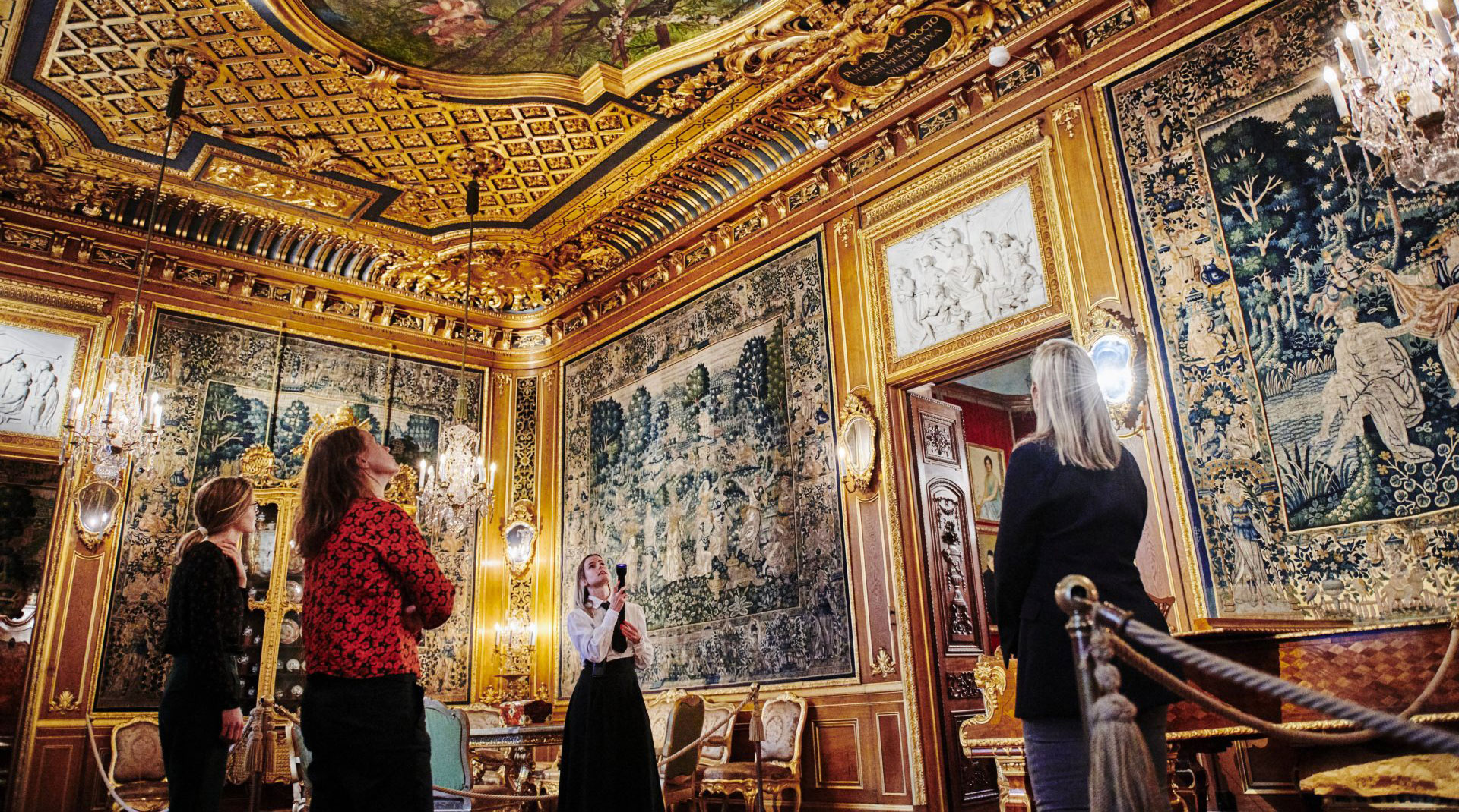 People on a guided tour in a golden room