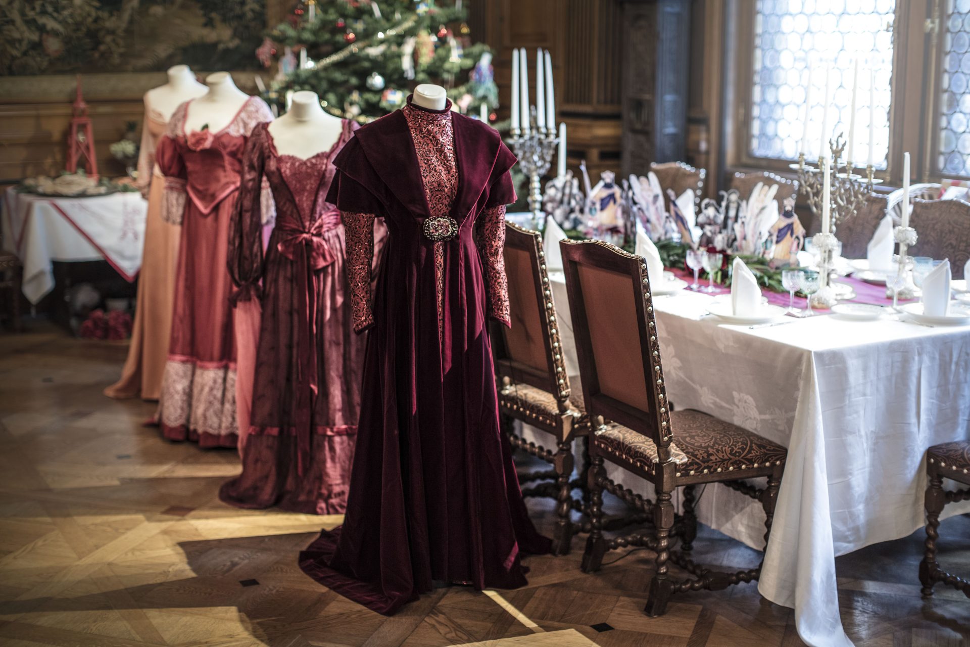 Julaftonsklänningar från filmen Fanny och Alexander som står uppradade i matsalen på Hallwylska museet.