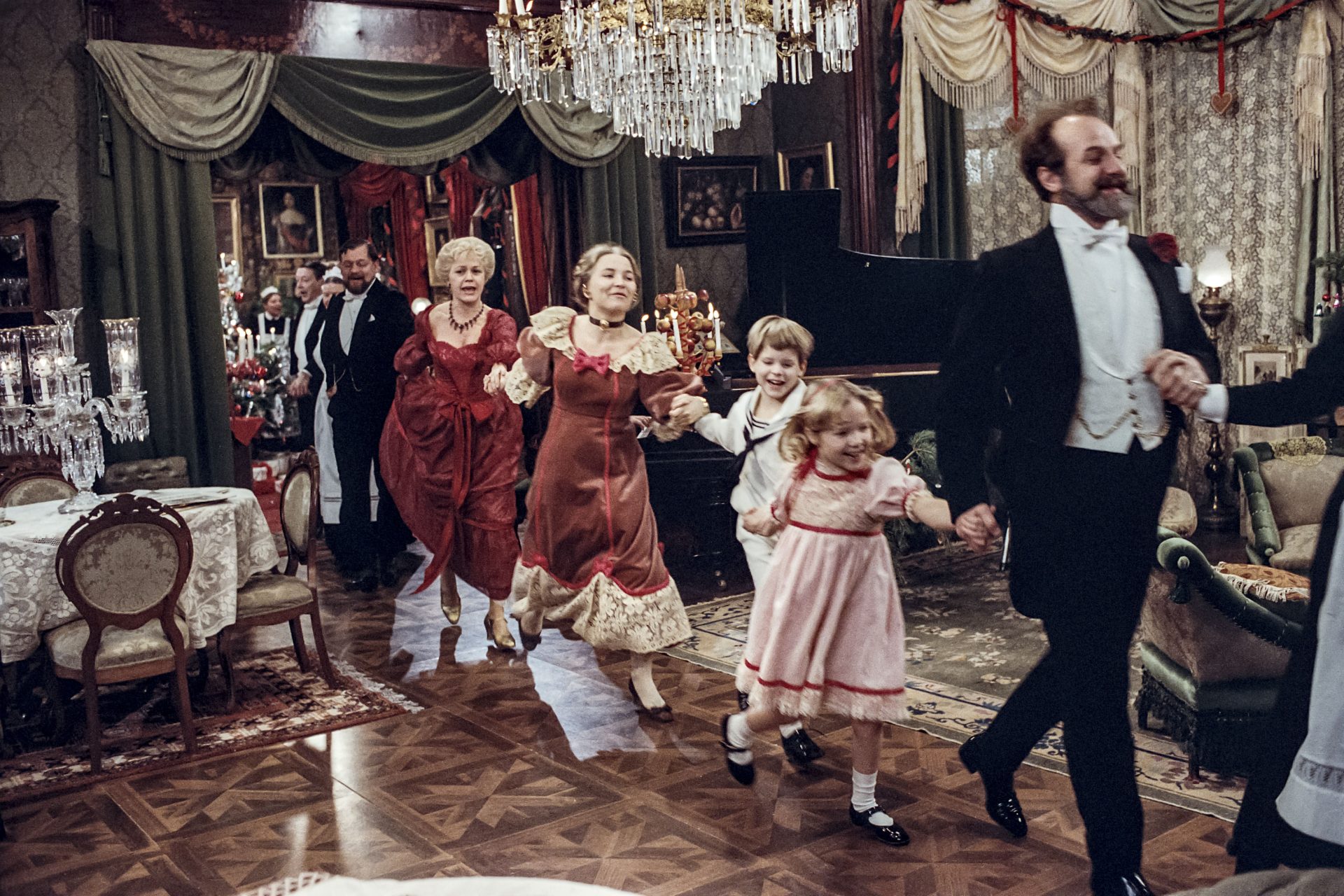 Bild ur filmen Fanny och Alexander där familjen dansar på led under julafton.