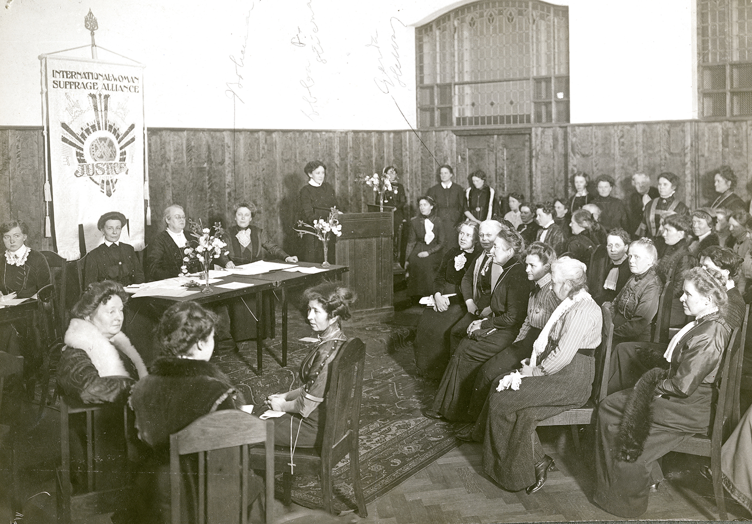 Svartvit bild på kvinnor som sitter på ett rösträttsmöte. 