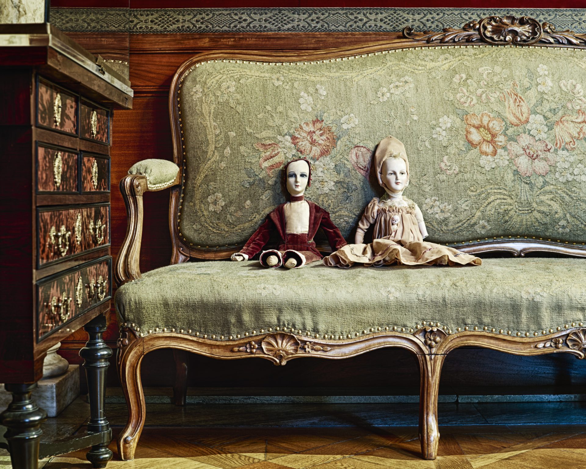 Ulrica Hydman Valliens dockor i en soffa i museets vardagssalong