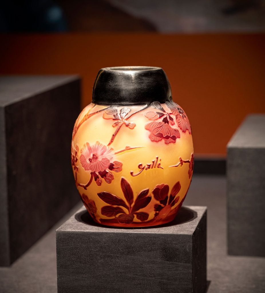 An orange vase with a pattern representing hawthorn berries and pink flowers