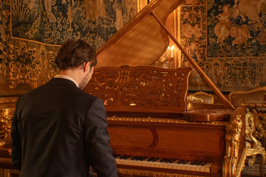 En pianist som sitter och spelar på flygen i Hallwylska palatset.