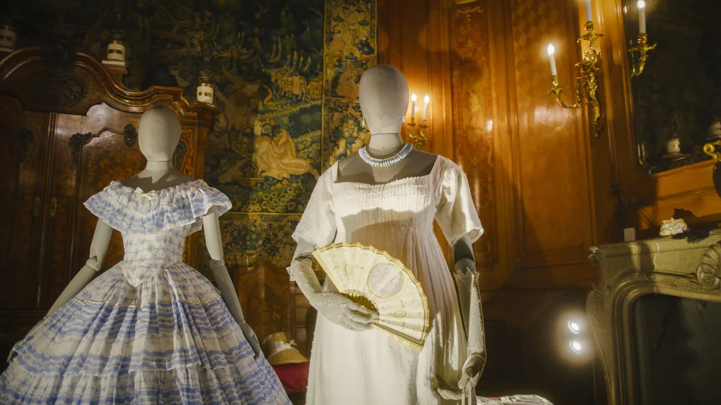 Two dresses on mannequins, one has a fan