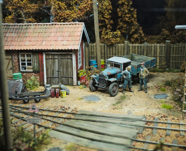A richly detailed miniature scene depicting a workshop area next to a railway track.