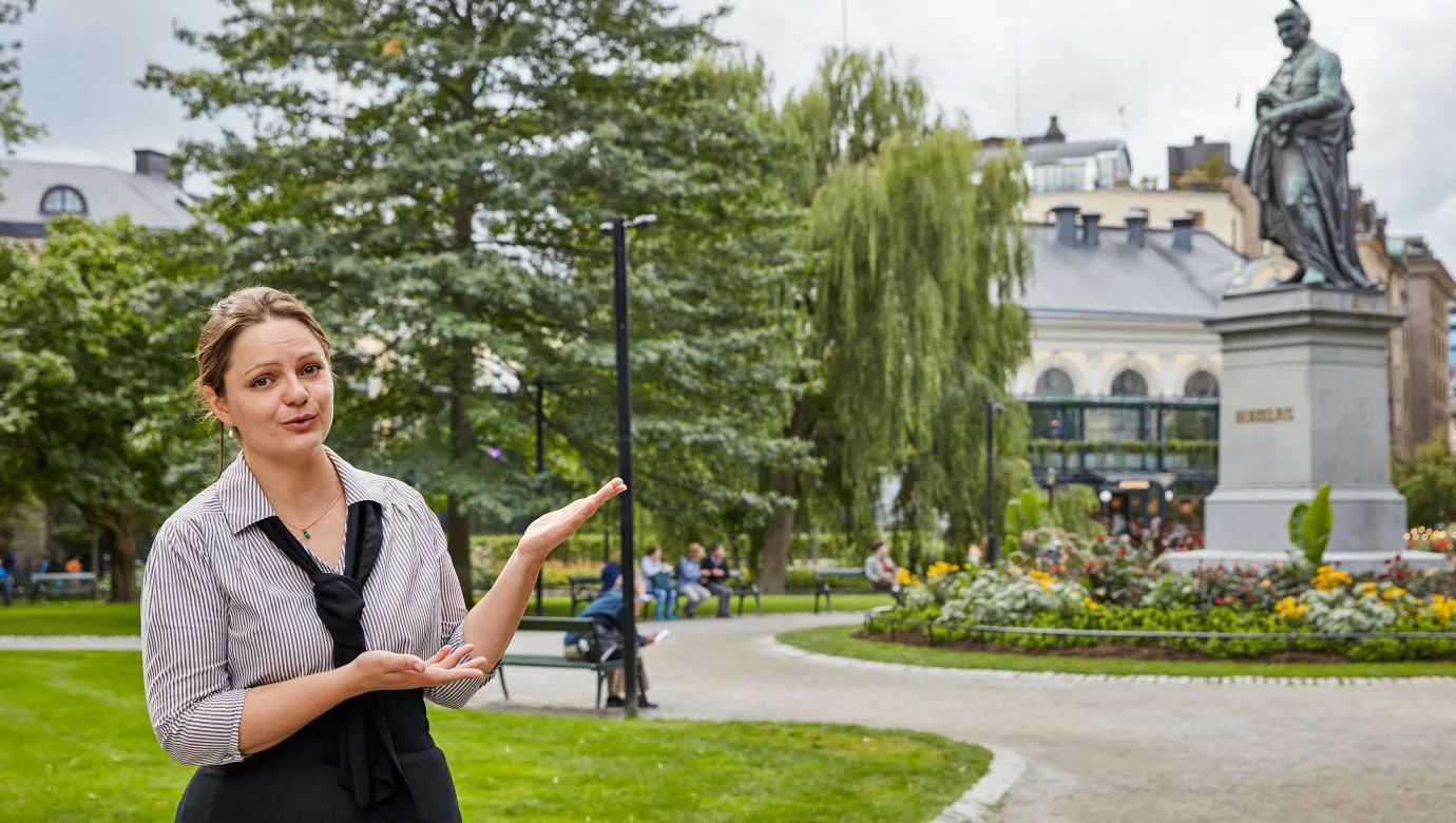 En guide som visar runt i berzelii park utanför museet.