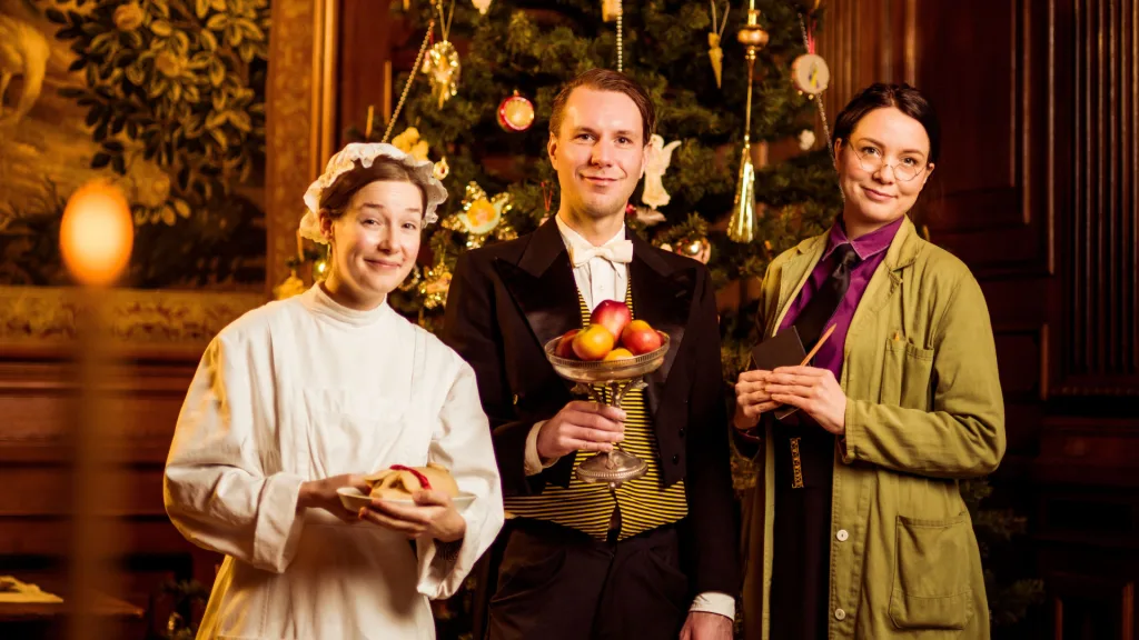 Tre personer framför en julgran.