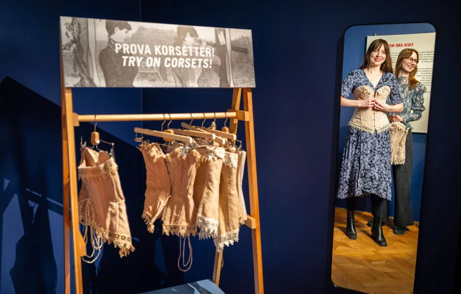 Korsetter att prova och två personer som provar korsetter.